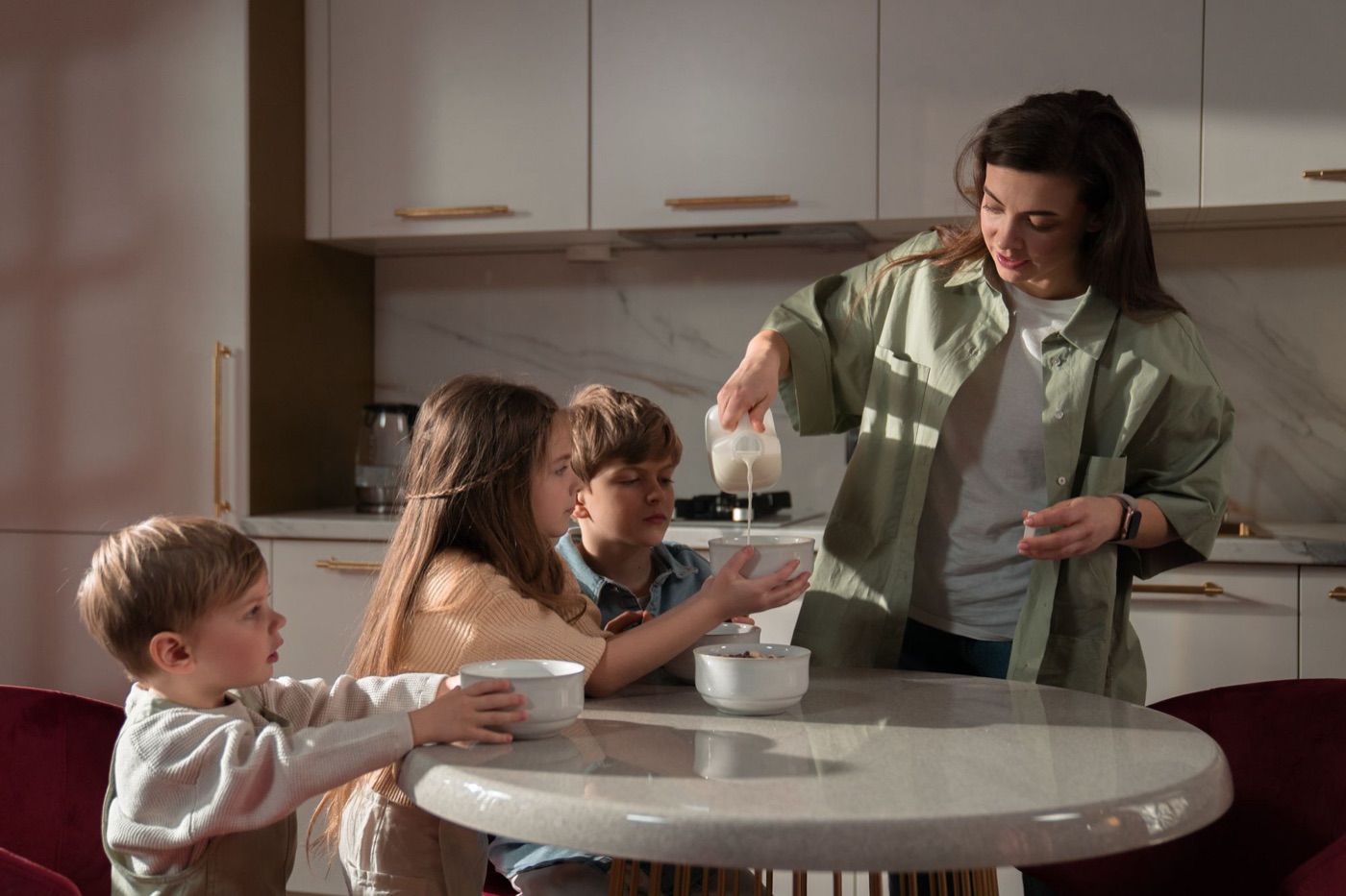 A mom pouring milk for her kids at the breakfast table
