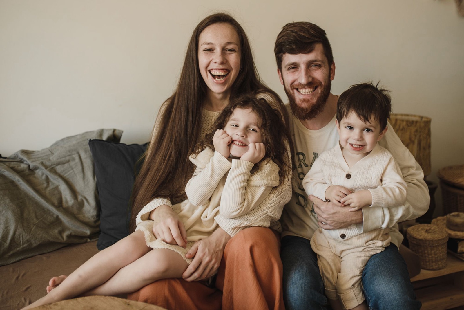 A happy family of four laughing together on the couch