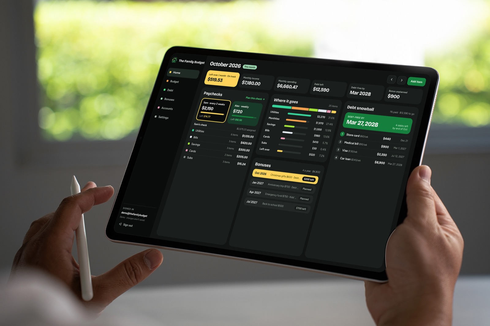 Hands holding a tablet showing The Family Budget home screen